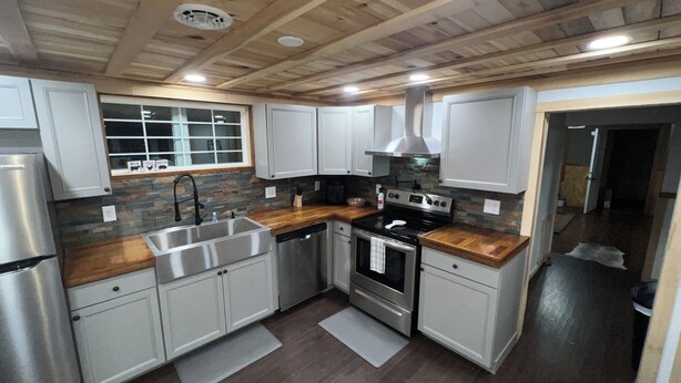 A modern kitchen with white cabinets, a stainless steel refrigerator, a black stove, and a wooden countertop. - Cannon Cliffside River Retreat-  FREE WIFI (Springfield)