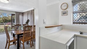 Une cuisine moderne avec une table et des chaises en bois, une horloge et une fenêtre donnant sur l’extérieur.
