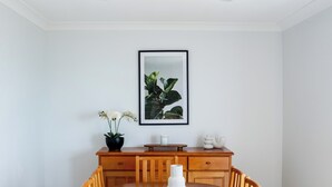 Un comedor con una mesa y sillas de madera, una planta en maceta y un cuadro en la pared.