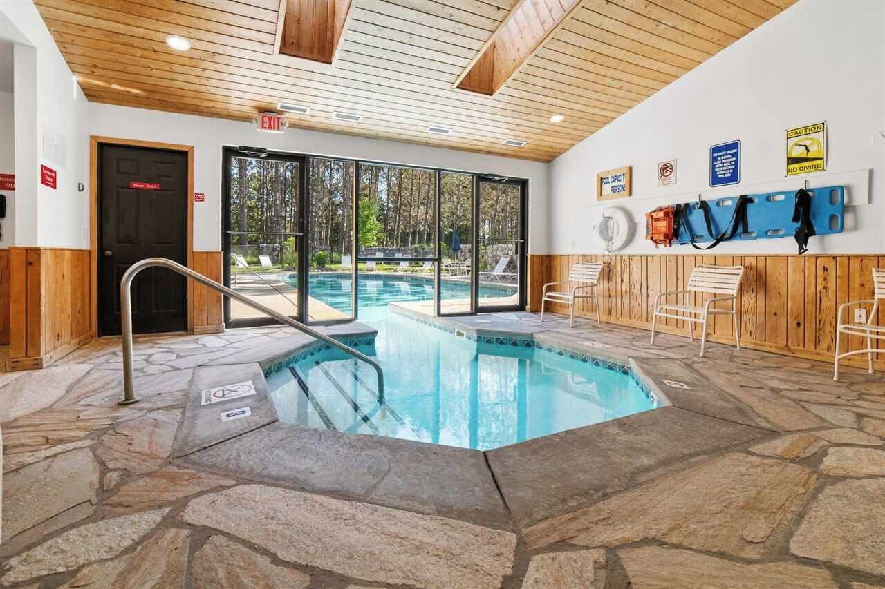 An indoor swimming pool with stone flooring, wooden walls, and a view of the outdoors.