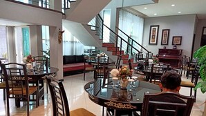 Un comedor espacioso con techo alto, una escalera y un piano.