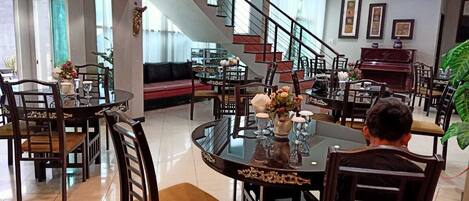 A spacious dining area with a high ceiling, a staircase, and a piano.