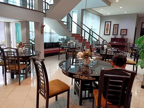 Un comedor espacioso con techo alto, una escalera y un piano.