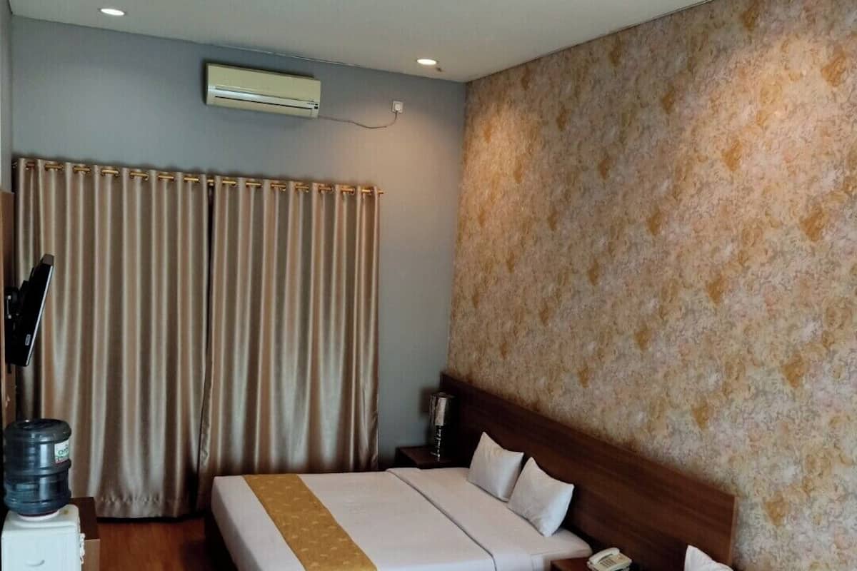 A hotel room with two beds, a wooden floor, a patterned wall, and an air conditioning unit.