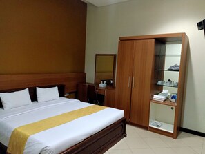 A hotel room with a bed, a wooden wardrobe, a mirror, and a shelf with toiletries.