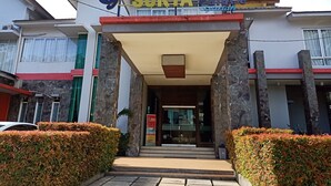 La entrada a un hotel llamado "Surya Palace", con un diseño arquitectónico moderno, fachada de piedra y un acceso despejado.