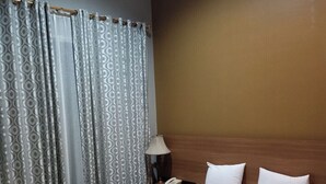 Una habitación de hotel con una cama grande, cabecera de madera, una mesita de noche con lámpara y un teléfono.