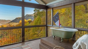 A bathroom with a bathtub, a flag, and a view of autumn foliage. - Whiteside Perch - Updated Home w/ Huge Views! Close to Everything!  (Highlands)