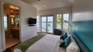 A bedroom with a bed, a television, a balcony with a view of the sea, and a ceiling fan. - "Gorgeous, 4-bedroom, 4.5-bathroom home with Beautiful Water and Sunset Views!" (George Town, Great Exuma)