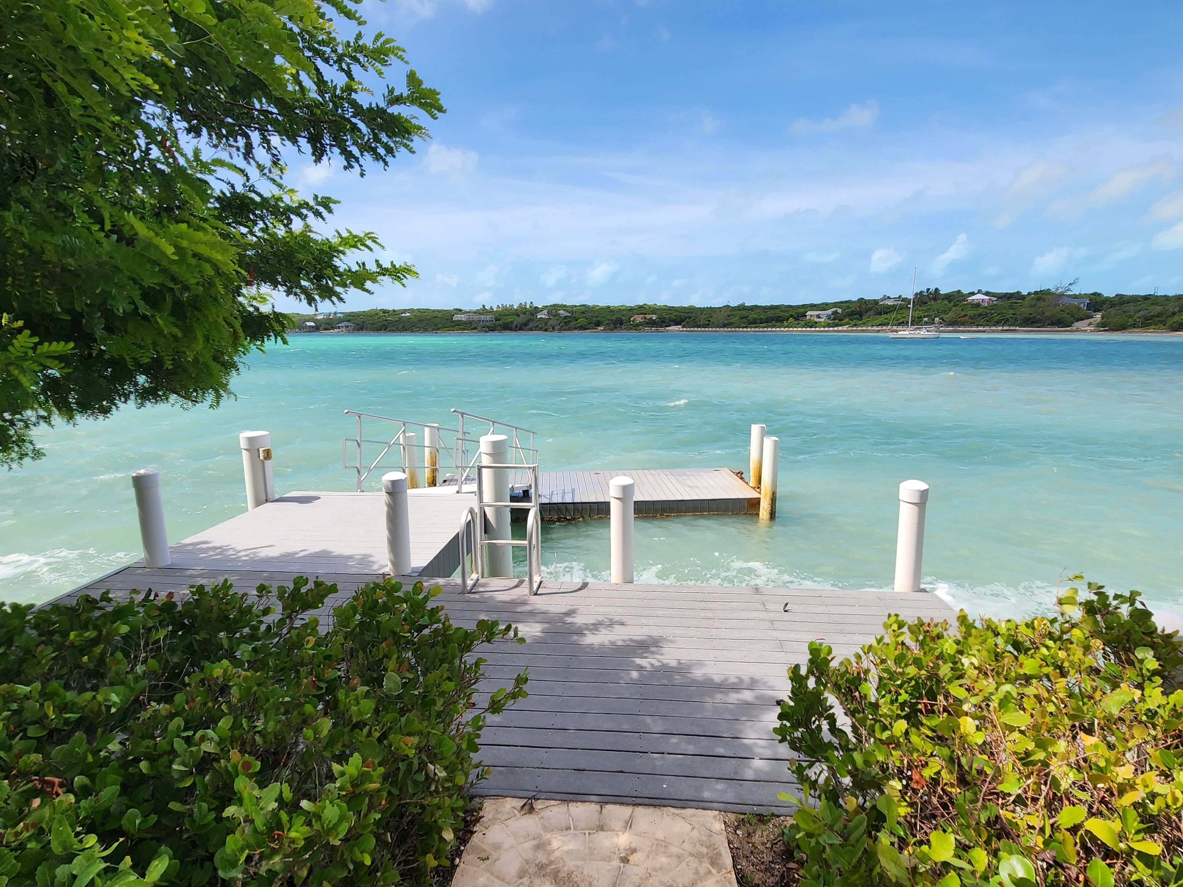 A wooden dock extending into clear turquoise waters with a small platform and railings.