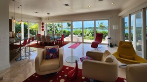 A spacious living room with a large glass door leading to a balcony with a view of the sea. - "Gorgeous, 4-bedroom, 4.5-bathroom home with Beautiful Water and Sunset Views!" (George Town, Great Exuma)