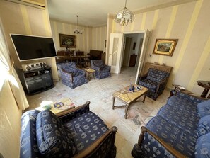 Een woonkamer met gestreept meubilair, een televisie en een eethoek met stoelen en een tafel.