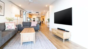 Un salon moderne avec un canapé, une table basse et un téléviseur fixé au mur.