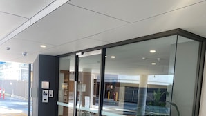 Een modern gebouw met glazen deuren, een beveiligingscodeklavier en een plant in een pot.