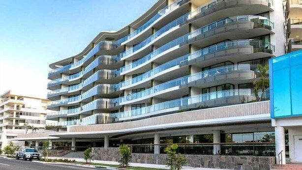 A multi-story hotel with a curved facade, balconies, and a covered parking area. - RIVERVIEWS@The Cosmopolitan Unit 20805 (Sunshine Coast)