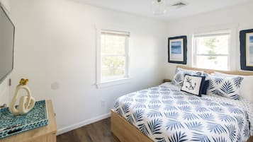 A bedroom with a bed, two windows, a ceiling light, and a wall-mounted picture.