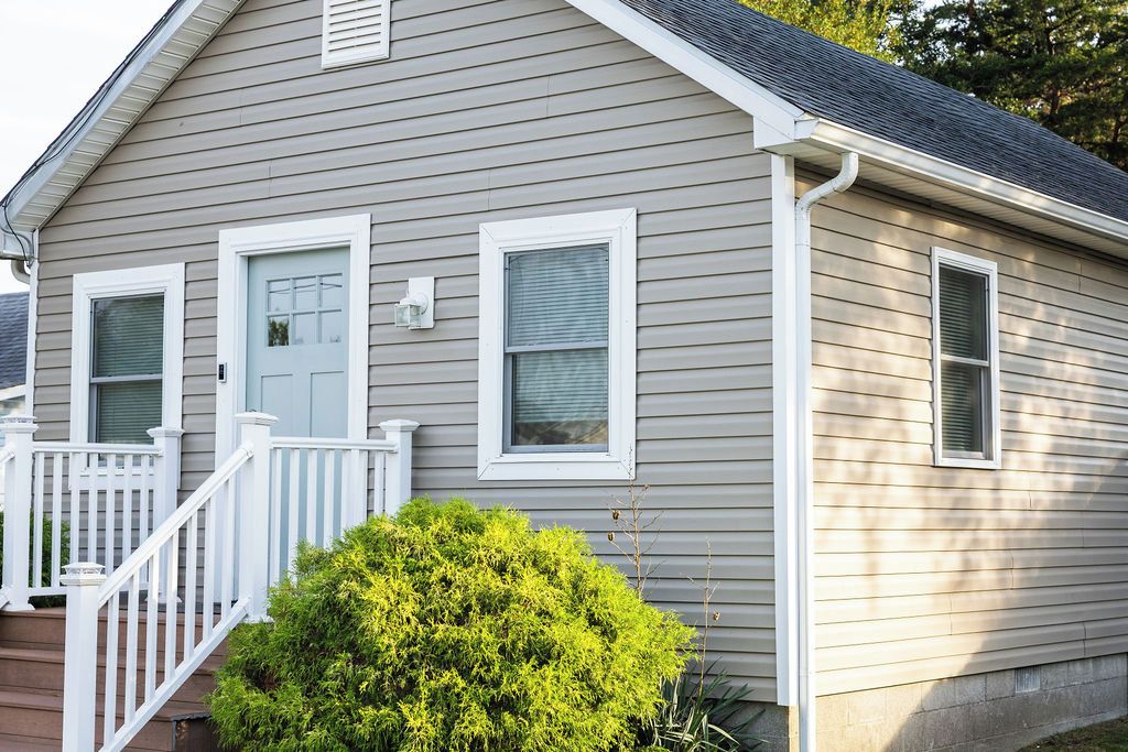 A residential house with a front porch, a door, and two windows.