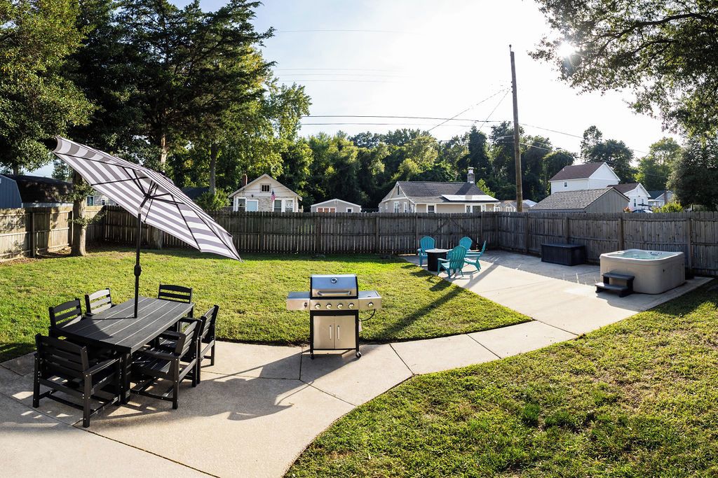 A backyard with a grill, patio furniture, and a hot tub.