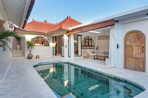 A modern pool area with a clear pool, white tiled flooring, and a wooden door. - Modern Trendy 3BR \ Seminyak \ 10min Beach \ Pool (Bali)
