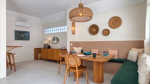 A modern dining area with a wooden table, chairs, and a hanging light fixture. - Modern Trendy 3BR \ Seminyak \ 10min Beach \ Pool (Bali)