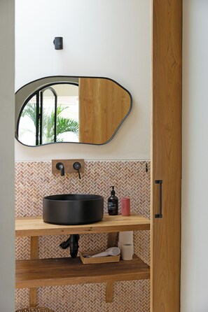 A bathroom with a wooden vanity, a round sink, a mirror with a wooden frame, and a tiled backsplash. - Modern Trendy 3BR \ Seminyak \ 10min Beach \ Pool (Bali)