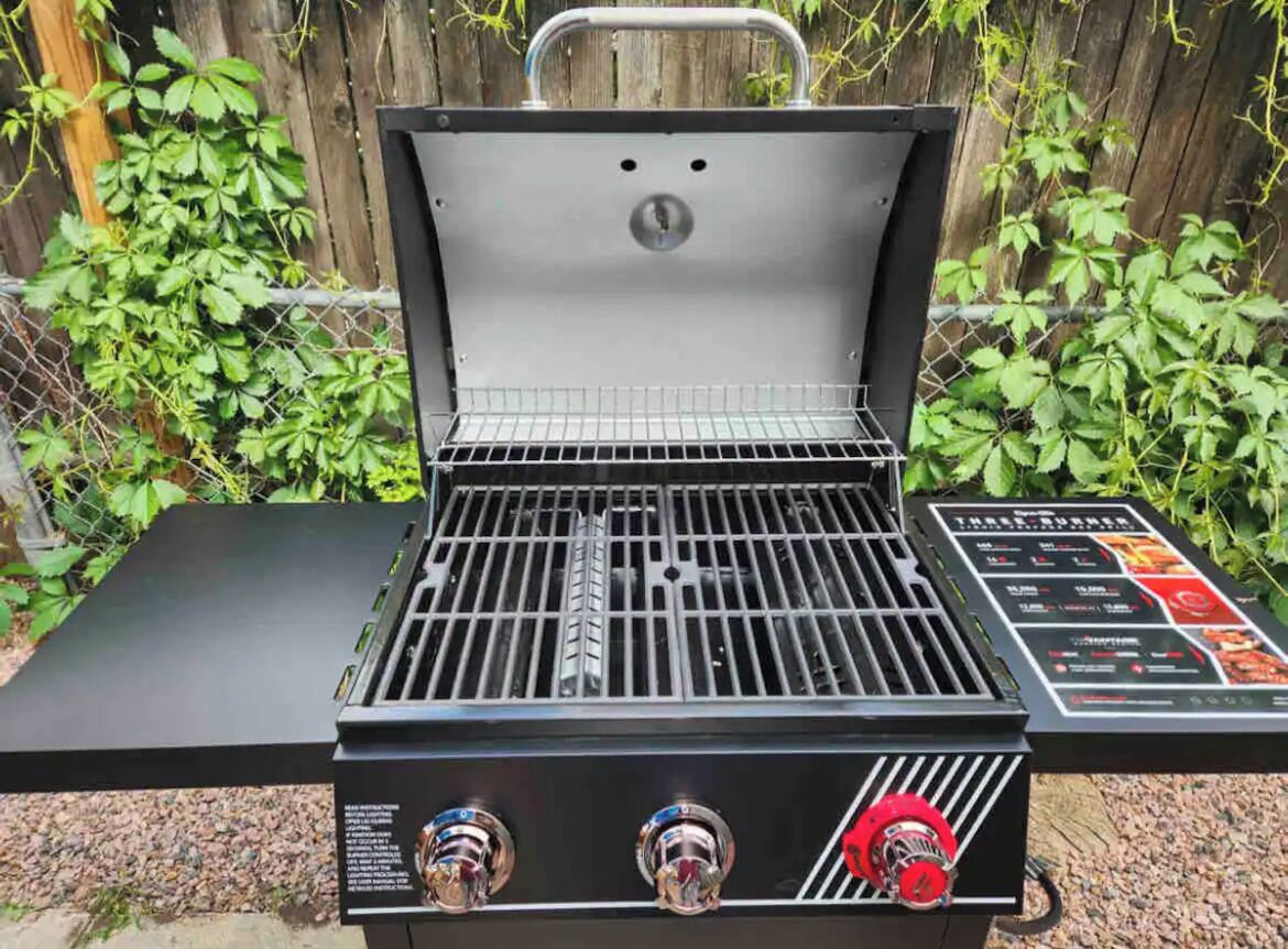 Una parrilla portátil con panel de control digital, rejilla metálica y asa.