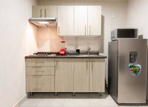 A kitchen with a stove, microwave, refrigerator, and cabinets. - Parques Guadalajara Department Condominium, Central, Comfortable (Guadalajara)