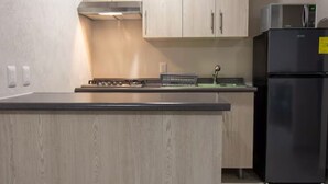A kitchen with a wooden countertop, a black refrigerator, and light-colored cabinets. - Parques Guadalajara Department Condominium, Central, Comfortable (Guadalajara)