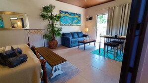 A living room with a sofa, a dining table, a coffee table, a potted plant, and a painting on the wall. - Suite Dream Blue Tu Descanso Soñado! Tamarindo Costa Rica (Provincia de Guanacaste)