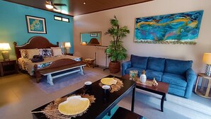 A hotel room with a bed, a blue sofa, a coffee table, a plant, and artwork on the walls. - Suite Dream Blue Tu Descanso Soñado! Tamarindo Costa Rica (Provincia de Guanacaste)