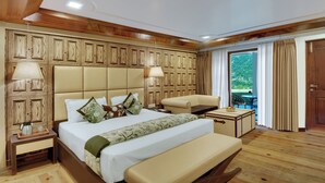 A hotel room with a large bed, a sofa, a small table, and a view of the outdoors. - Dyo - The Organic Village Resort (Dhari)