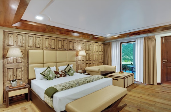 A hotel room with a large bed, a sofa, a small table, and a view of the outdoors. - Dyo - The Organic Village Resort (Dhari)