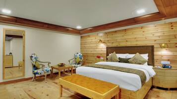 A wooden-paneled bedroom with a bed, two chairs, a small table, and a bench.