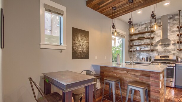 Una cocina moderna con una isla de madera, taburetes de bar y una estufa empotrada.
