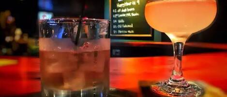 Two drinks on a bar counter with a sign in the background.
