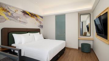 Quarto de hotel moderno com uma cama grande, televisão de tela plana, um espelho e um banquinho verde.
