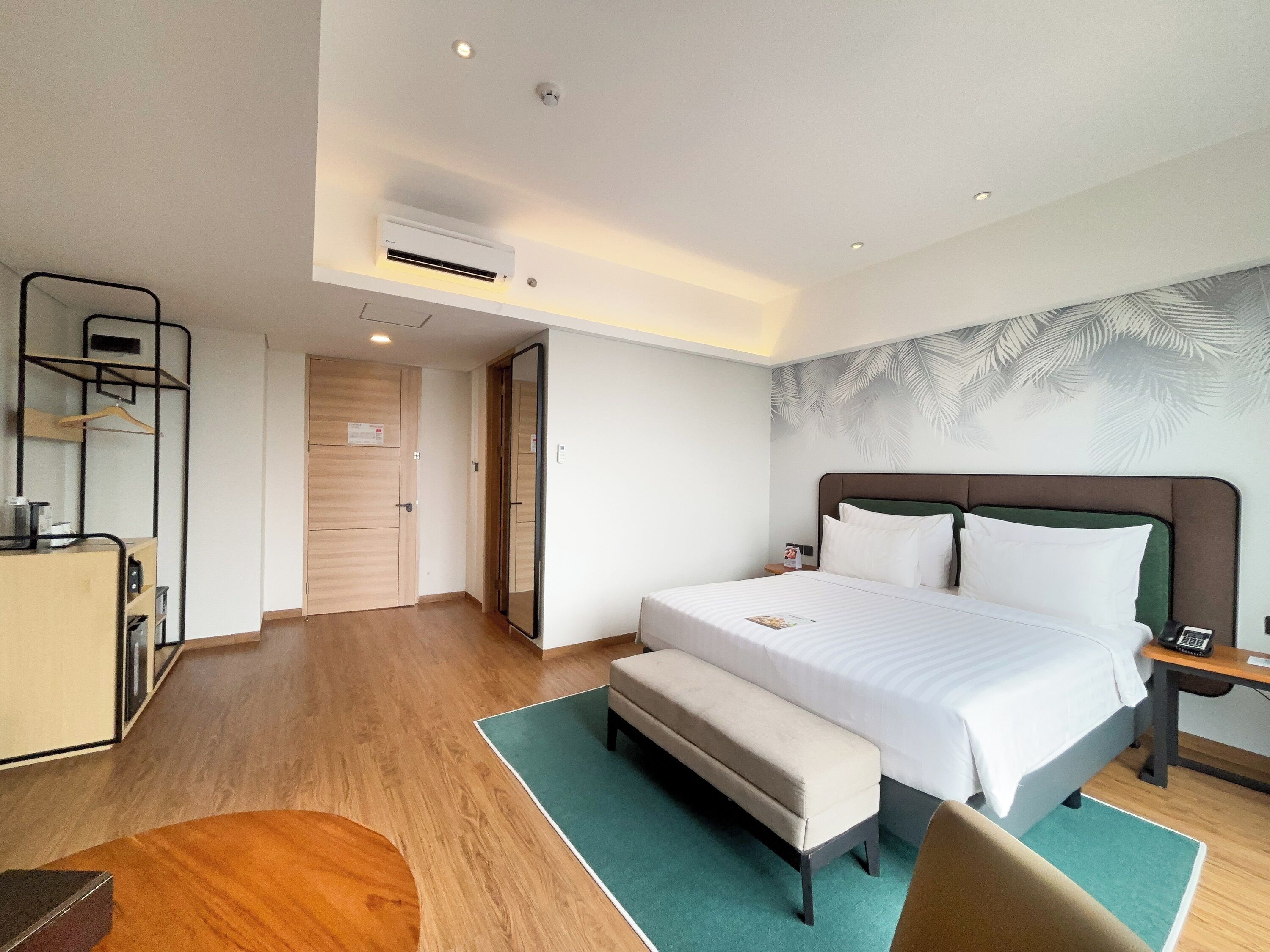 Une chambre d’hôtel avec un grand lit, un banc, un bureau et une armoire.