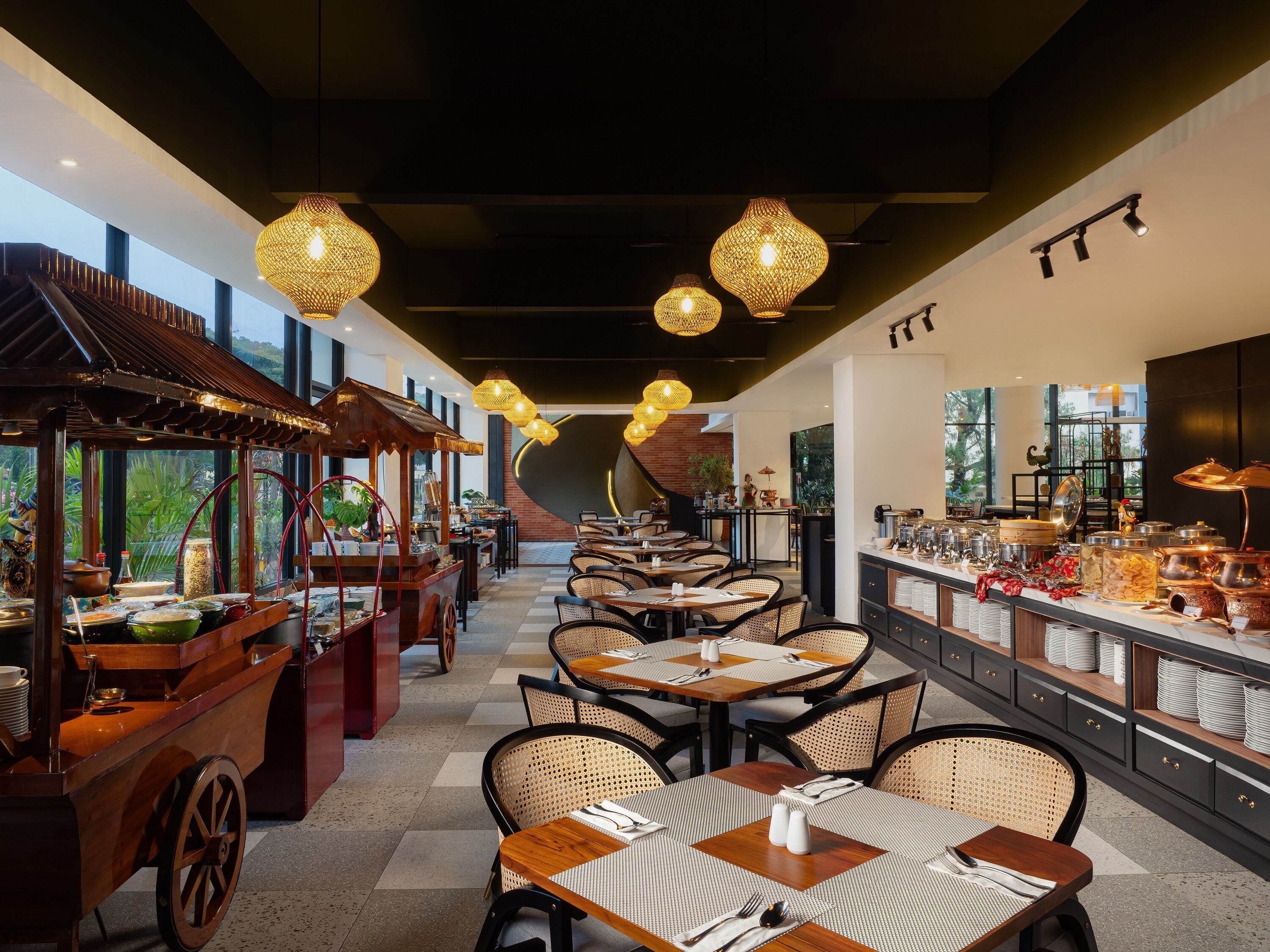 A restaurant with a long counter, wicker chairs, and hanging lights.