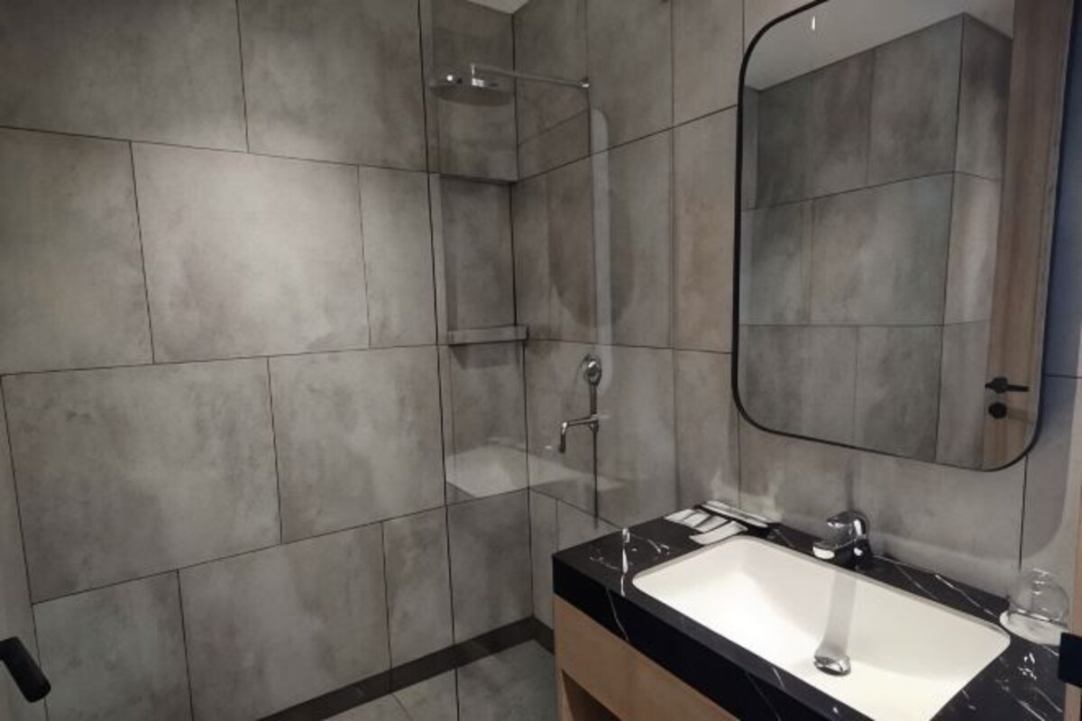 Un baño con cabina de ducha de vidrio, lavabo con espejo y paredes de azulejos.