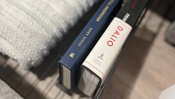 A close-up of a bookshelf with books and a white knitted blanket.