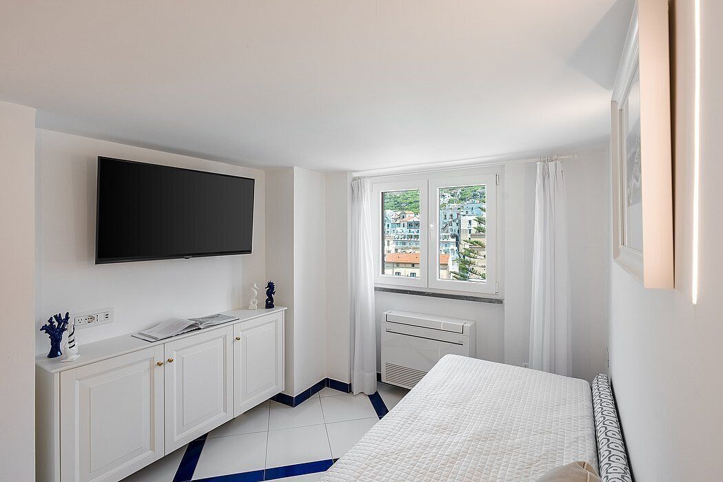 A hotel room with a bed, a TV mounted on the wall, a window with curtains, and a radiator.