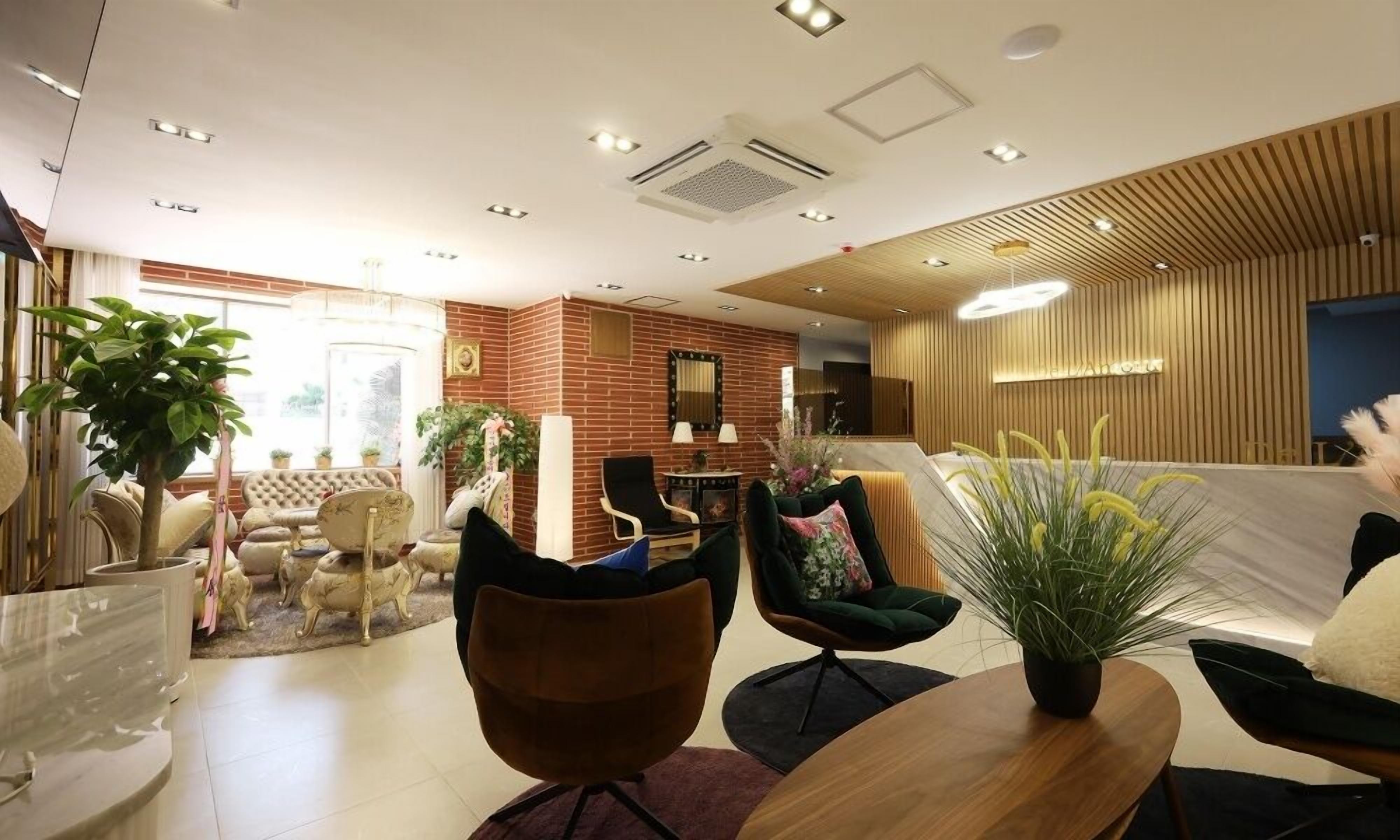 En modern hotellobby med en tegelvägg, en sittgrupp och krukväxter.