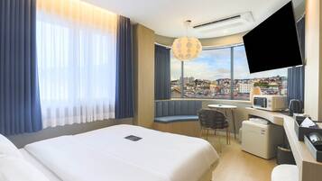 Una camera d'albergo con un letto, una scrivania con un forno a microonde, una sedia e una televisione.