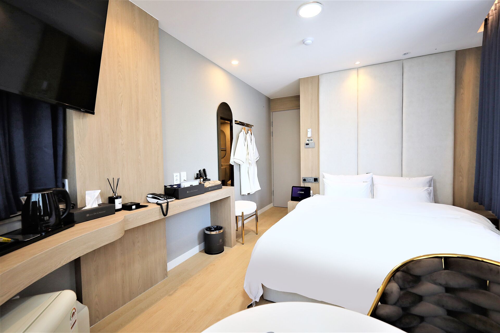 Ein Hotelzimmer mit einem Bett, einem Schreibtisch mit Kaffeemaschine, einem Fernseher und einem Spiegel.