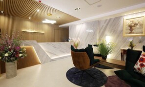 A modern hotel lobby with a reception desk, seating area, and decorative plants. - DELAMOUR Hotel (Tongyeong)