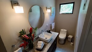 Une salle de bain avec un lavabo, un miroir, des toilettes et une fenêtre.