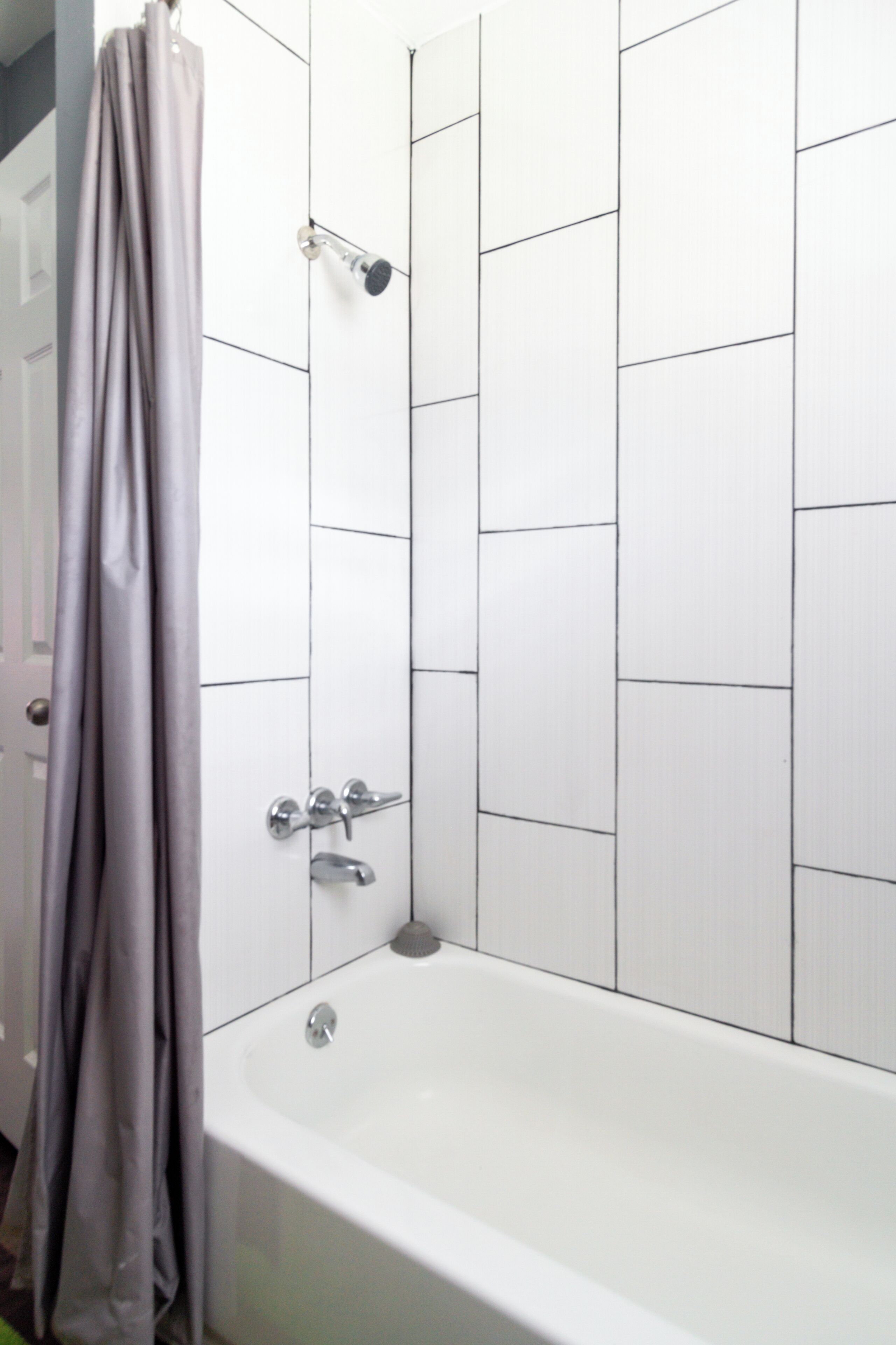 A bathroom with a white bathtub, a showerhead, and a curtain.