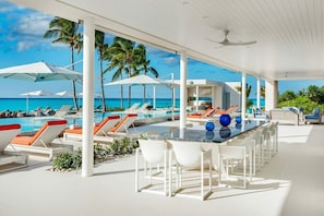 Relax by the ocean with a refreshing dip in the pool, surrounded by comfortable lounge chairs and a shaded bar area.
