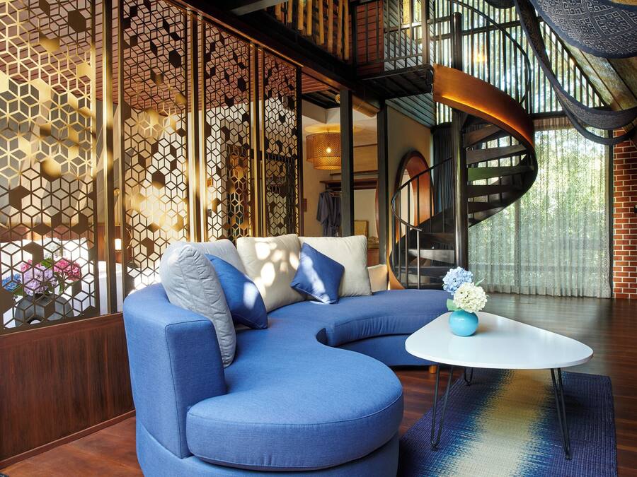 Una sala de estar moderna con un sofá seccional azul, una mesa de centro blanca y una pared decorativa con patrones geométricos.