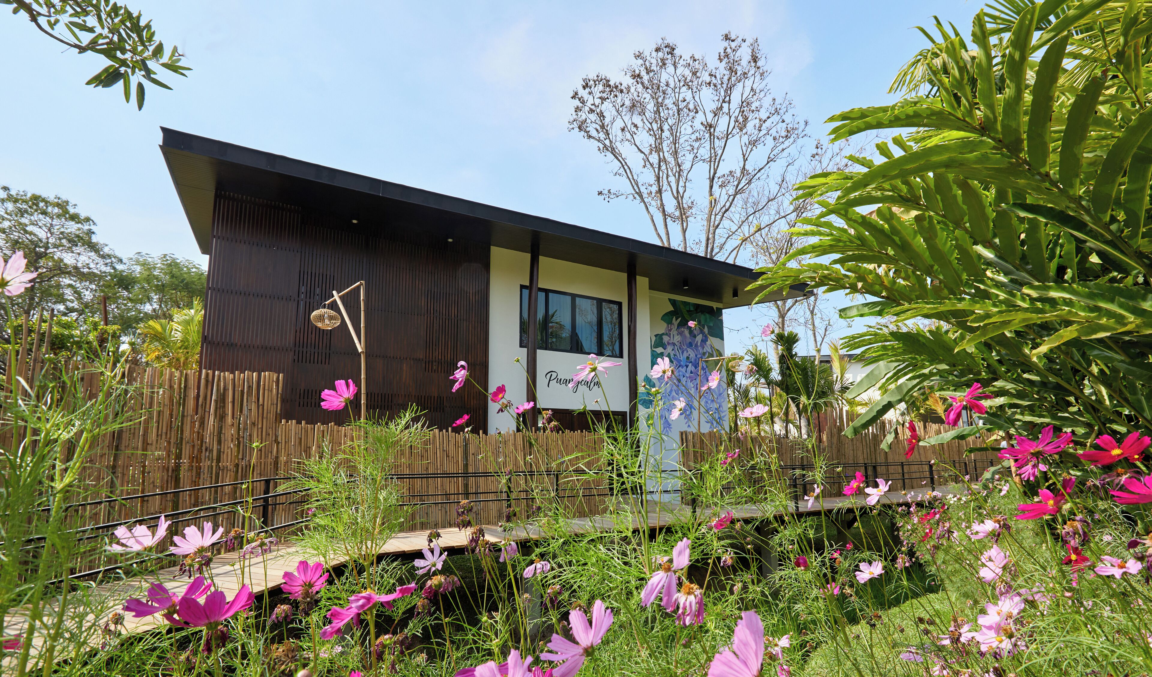 A modern building with a wooden fence and vibrant pink flowers in the foreground.